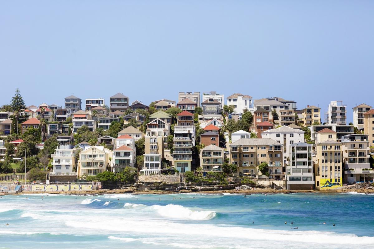 Coastal apartment buildings and hillside homes overlooking a sandy beach and blue sea